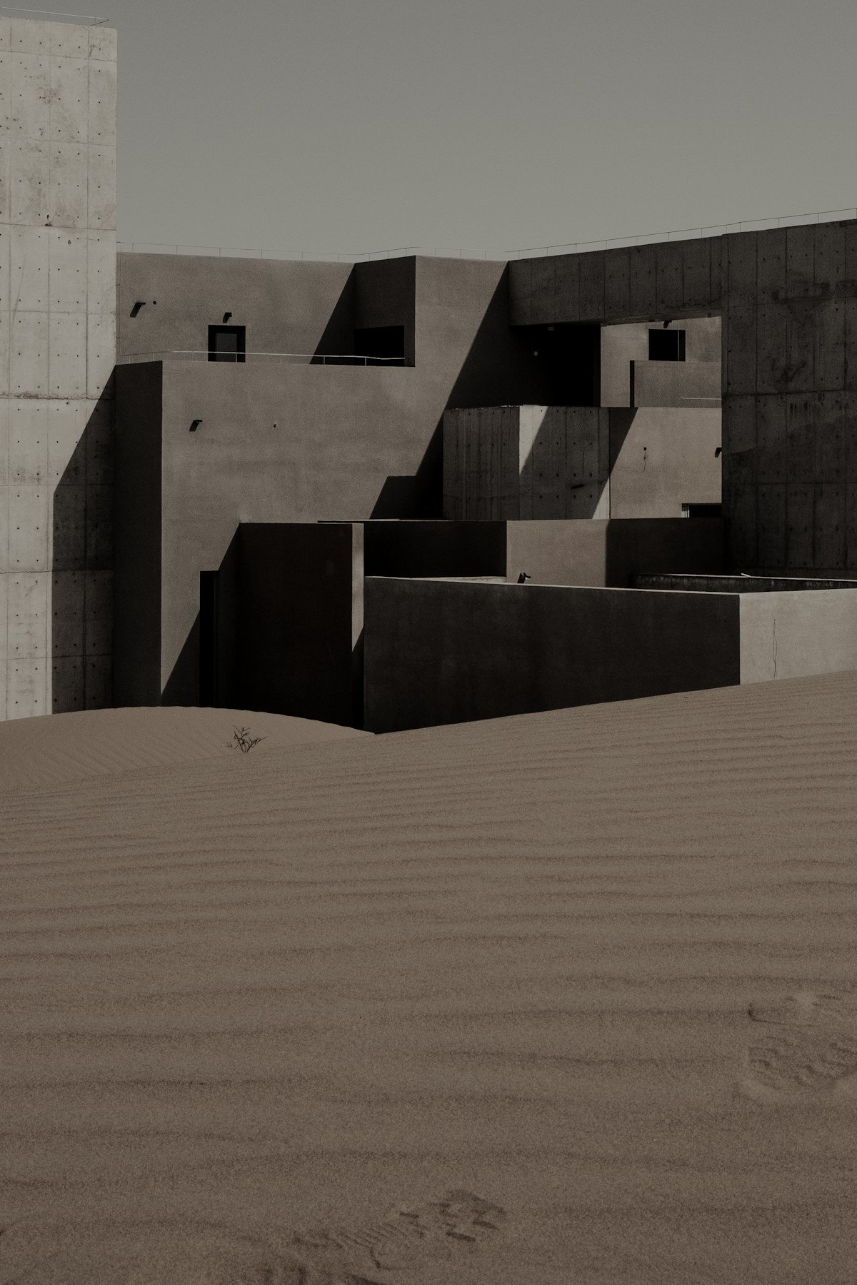 A concrete volume half-buried in a dune.