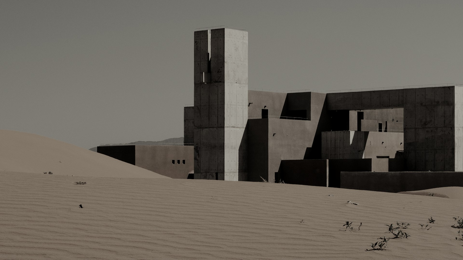 The cluster of concrete volumes seen from far away across the dunes.