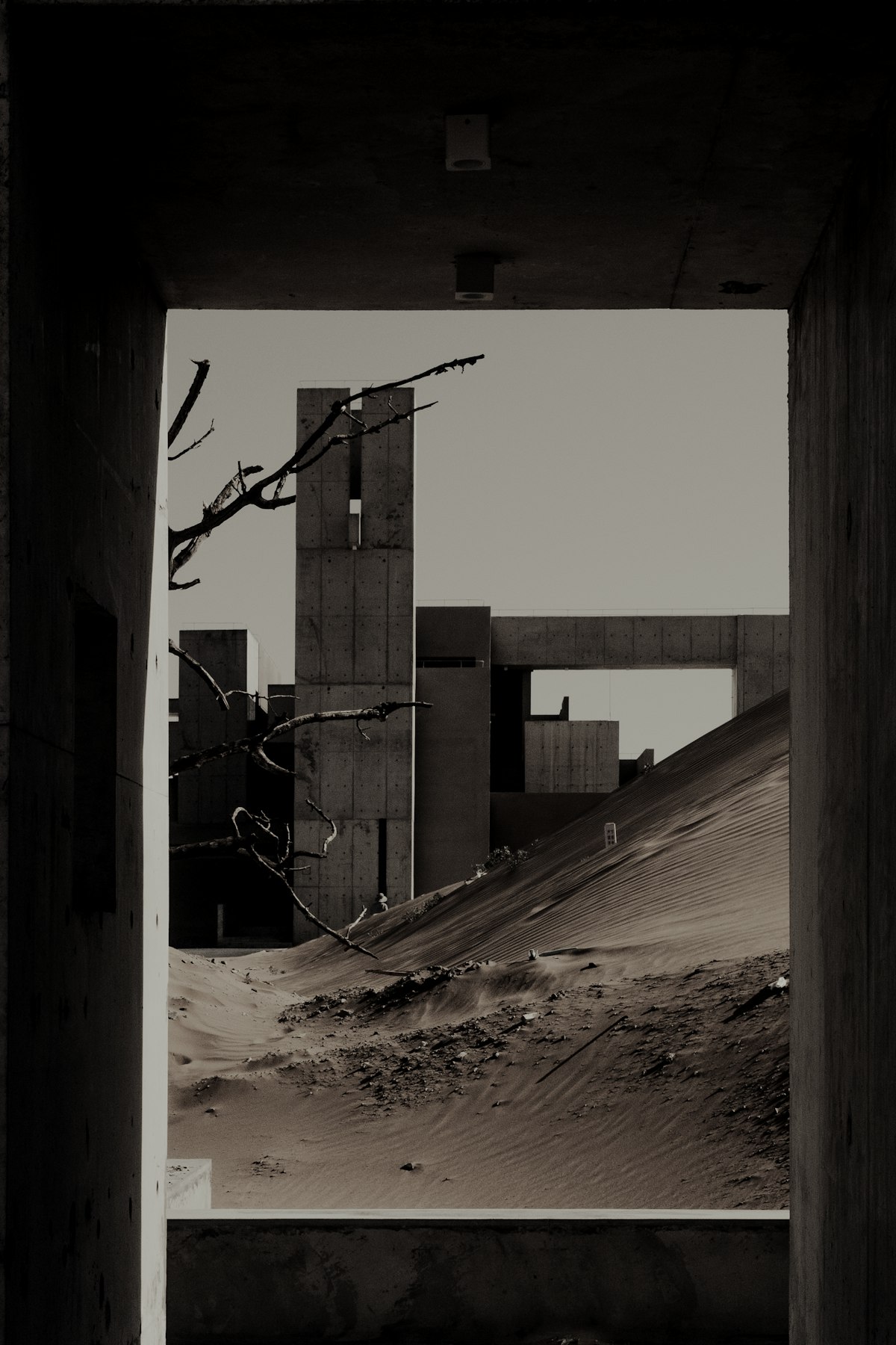 Concrete volumes and dunes seen through a deep concrete frame.