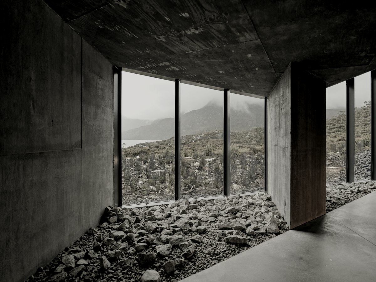 The garden room of Kitayama House: a gravel floor, concrete walls and tall windows onto a wooded valley.