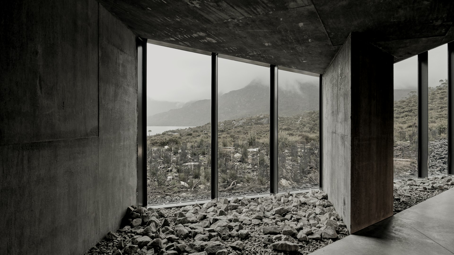 The garden room of Kitayama House: a gravel floor, concrete walls and tall windows onto a wooded valley.