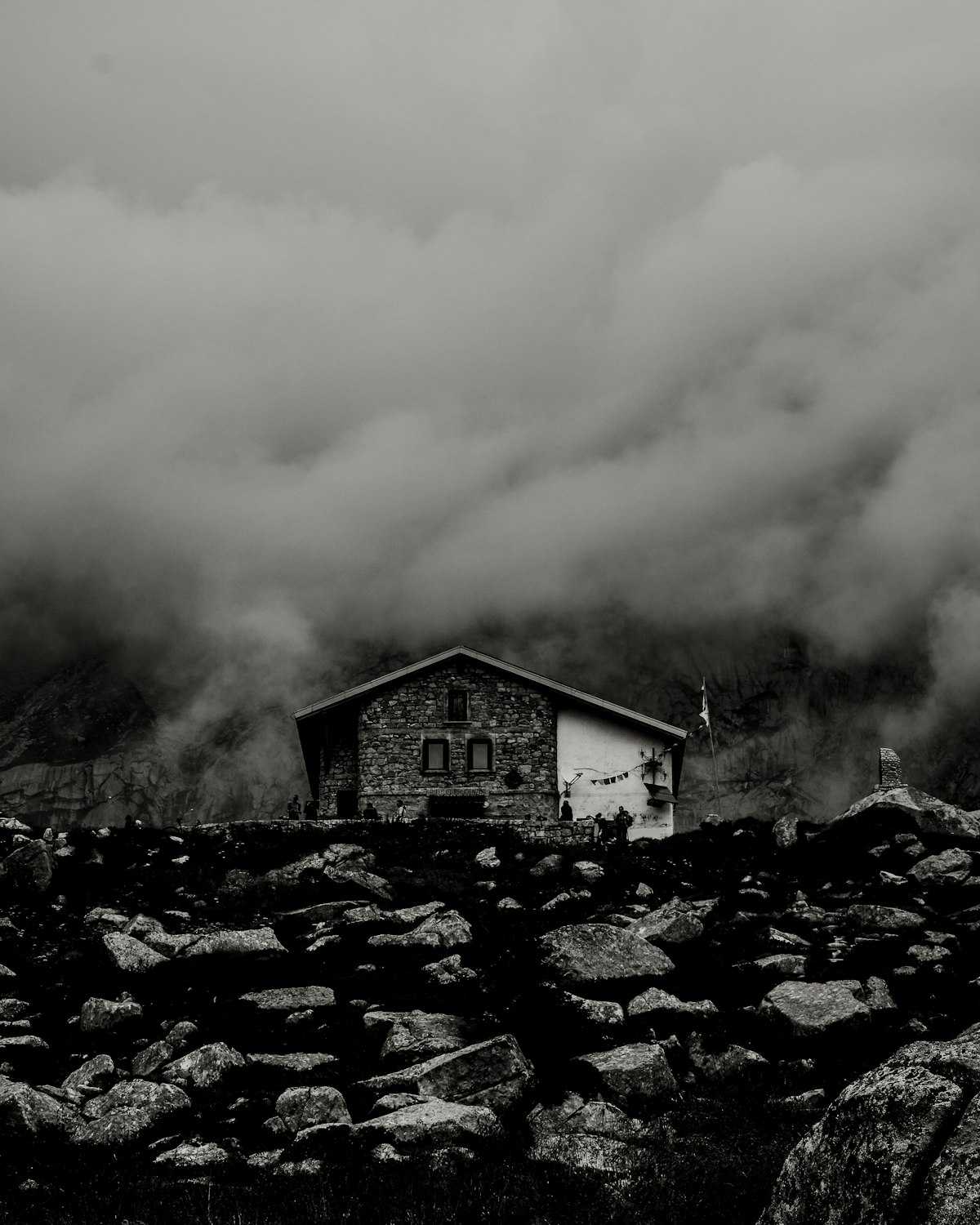 A small dry-stone refuge on a rocky ridge, wrapped in cloud.